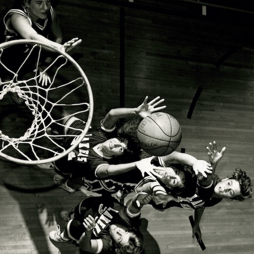 Aerial shot of hoop and Mundelein basketball team members leaping for the basketball