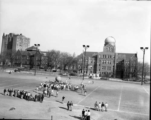 A crowd of Loyola University Chicago students play a game of pushball on the field outside Cudahy Science Hall.