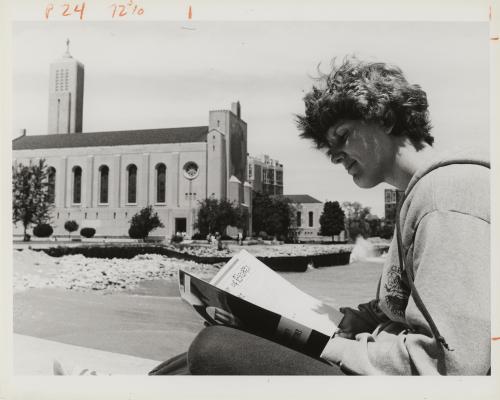 A Loyola University Chicago student sits outside Madonna Della Strada chapel by Lake Michigan, reading a book.
