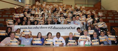 Stritch School of Medicine students and faculty in a lecture hall with banners and signs promoting #Educators Out and the Dream Act.